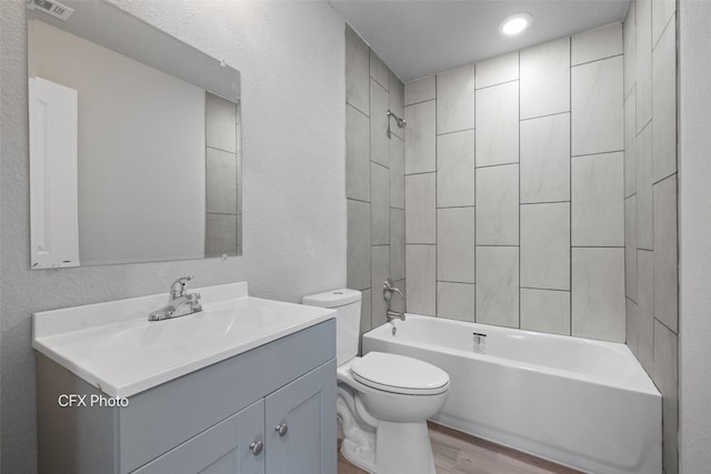 full bathroom with tiled shower / bath combo, toilet, vanity with extensive cabinet space, and hardwood / wood-style flooring