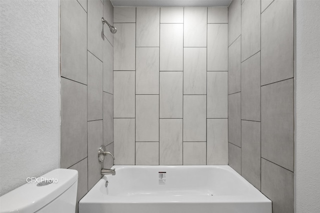 bathroom featuring toilet and tiled shower / bath