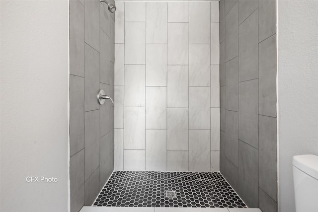 bathroom featuring toilet and tiled shower