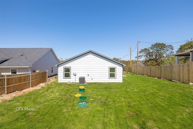 back of house with central air condition unit and a lawn