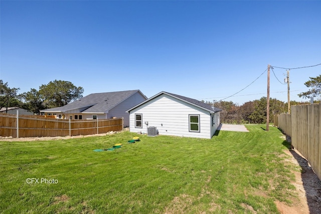 rear view of property featuring central AC unit and a yard