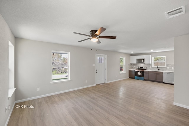 unfurnished living room featuring ceiling fan, sink, and light hardwood / wood-style floors