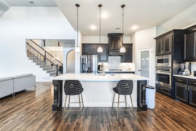 kitchen featuring pendant lighting, premium range hood, appliances with stainless steel finishes, backsplash, and dark hardwood / wood-style flooring