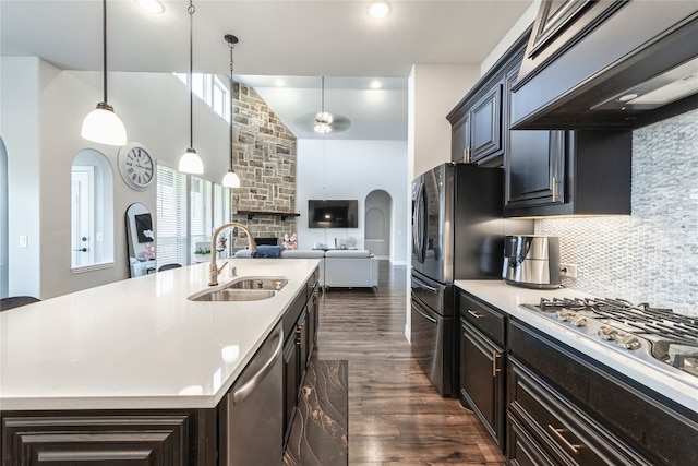 kitchen featuring dark wood-type flooring, a stone fireplace, pendant lighting, premium range hood, and sink