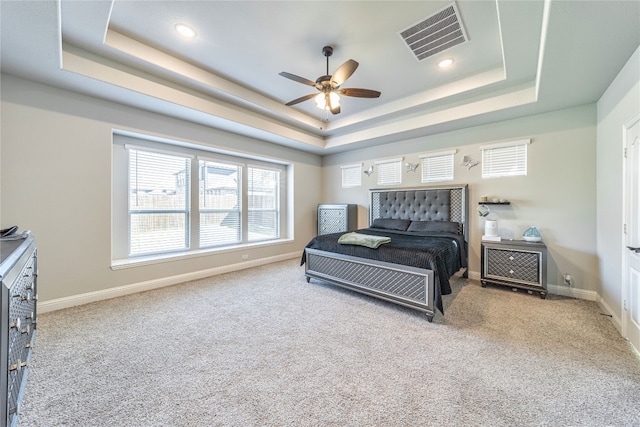 bedroom featuring a raised ceiling, ceiling fan, and light carpet