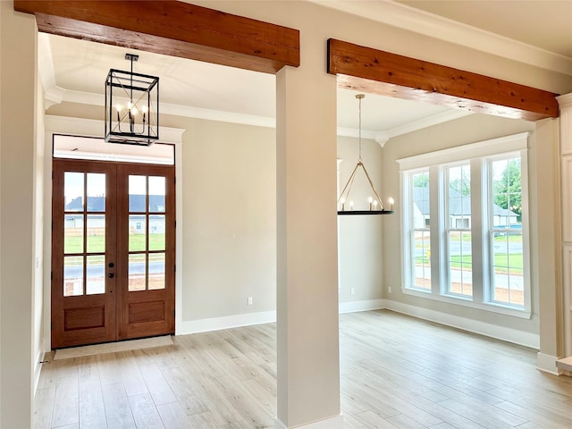 foyer with an inviting chandelier, light wood-type flooring, ornamental molding, beam ceiling, and french doors