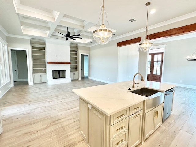 kitchen with pendant lighting, stainless steel dishwasher, light stone countertops, and an island with sink