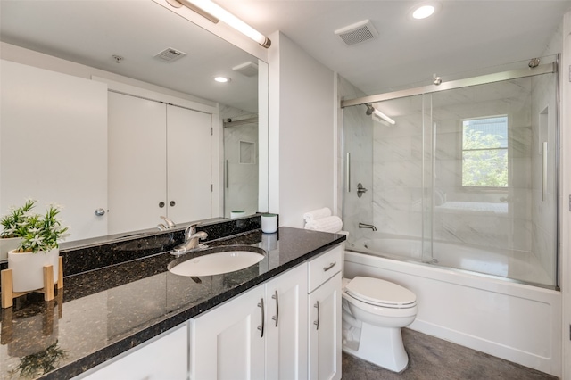 full bathroom featuring toilet, bath / shower combo with glass door, and vanity with extensive cabinet space