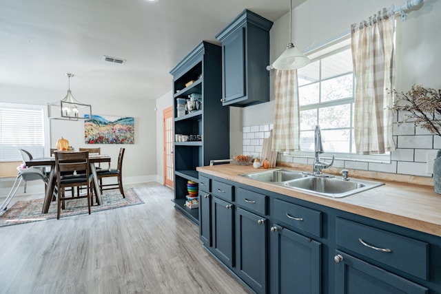 kitchen featuring sink, decorative light fixtures, and wooden counters