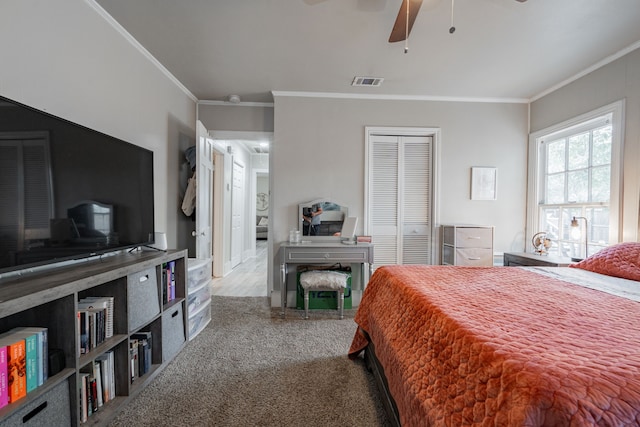 carpeted bedroom with a closet, ceiling fan, and crown molding