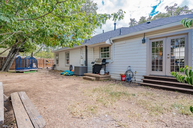 rear view of house featuring a trampoline and central AC unit