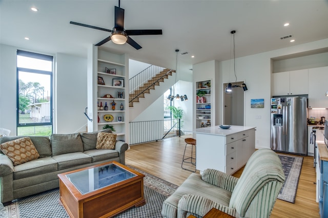 living area featuring plenty of natural light, light wood-style flooring, built in shelves, and visible vents