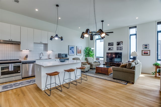 kitchen featuring white cabinets, a kitchen island, appliances with stainless steel finishes, a breakfast bar area, and a sink