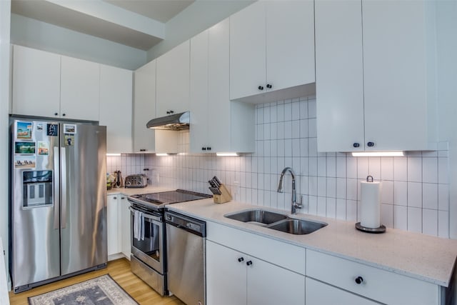 kitchen with under cabinet range hood, tasteful backsplash, appliances with stainless steel finishes, and a sink