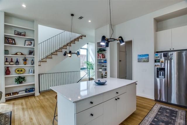 kitchen featuring open shelves, stainless steel refrigerator with ice dispenser, a kitchen island, and visible vents