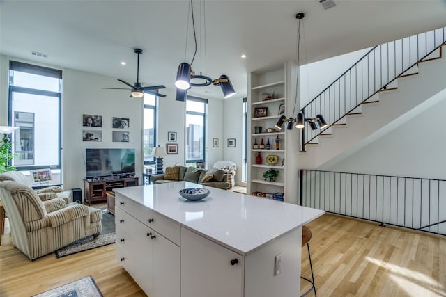 kitchen with a center island, light wood-style floors, open floor plan, white cabinets, and a kitchen breakfast bar