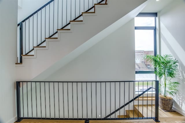 stairway featuring baseboards, floor to ceiling windows, and wood finished floors