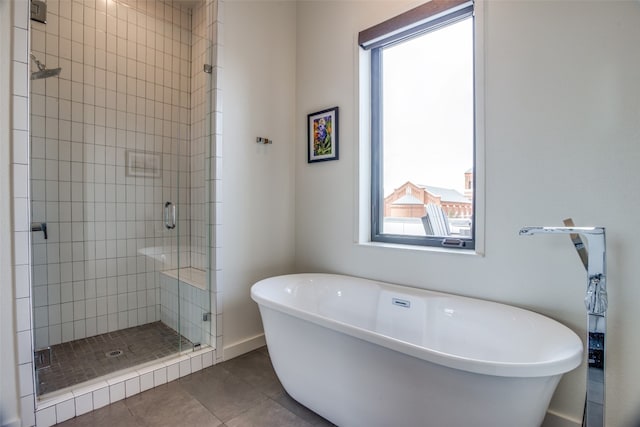 bathroom with baseboards, a stall shower, a freestanding tub, and tile patterned floors