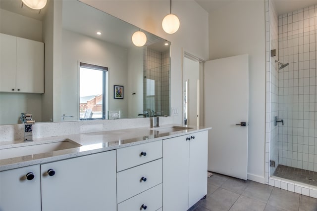 bathroom featuring double vanity, a stall shower, tile patterned flooring, and a sink