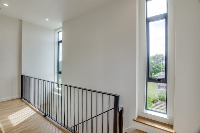 corridor featuring baseboards, wood finished floors, a wealth of natural light, and recessed lighting