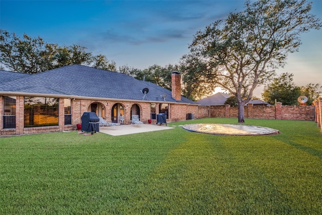 back of house featuring a patio area, a yard, and brick siding