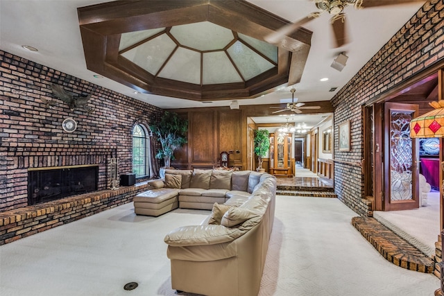 living room featuring ceiling fan, brick wall, a brick fireplace, and light colored carpet