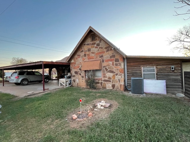 view of side of property with a yard, central AC, and a carport