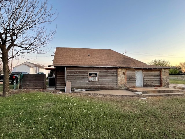 property exterior at dusk with a lawn and a patio area