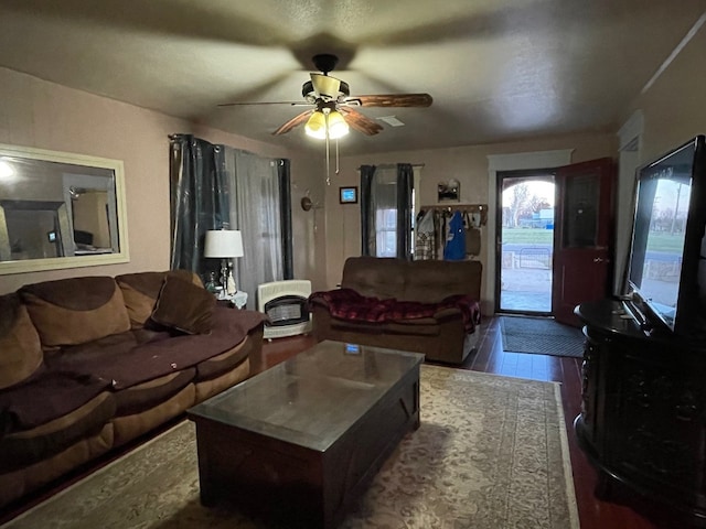 living room featuring dark wood-type flooring and ceiling fan