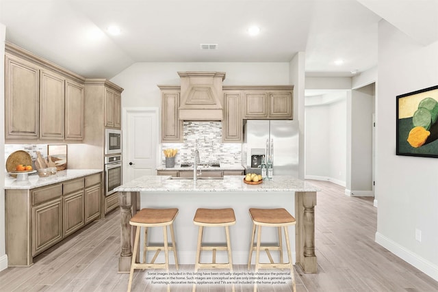 kitchen featuring backsplash, custom range hood, light hardwood / wood-style floors, a center island with sink, and stainless steel appliances