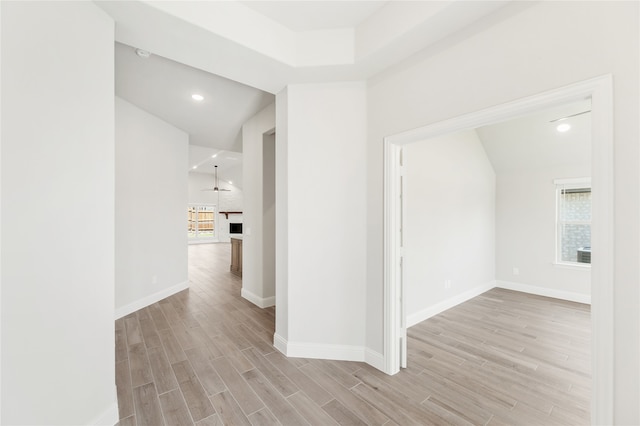 hallway with light hardwood / wood-style floors, a healthy amount of sunlight, and lofted ceiling