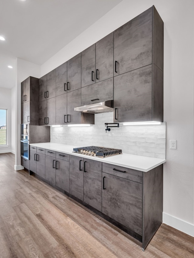 kitchen featuring stainless steel gas cooktop, light hardwood / wood-style flooring, and backsplash