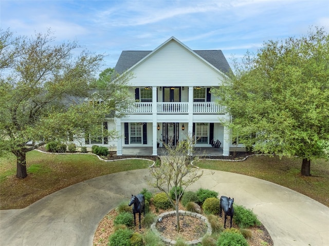 view of front facade with a balcony, a porch, and a front lawn