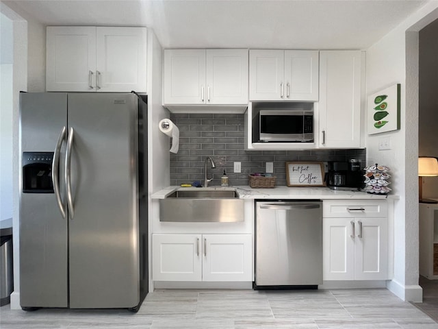 kitchen with sink, light stone counters, white cabinets, appliances with stainless steel finishes, and backsplash