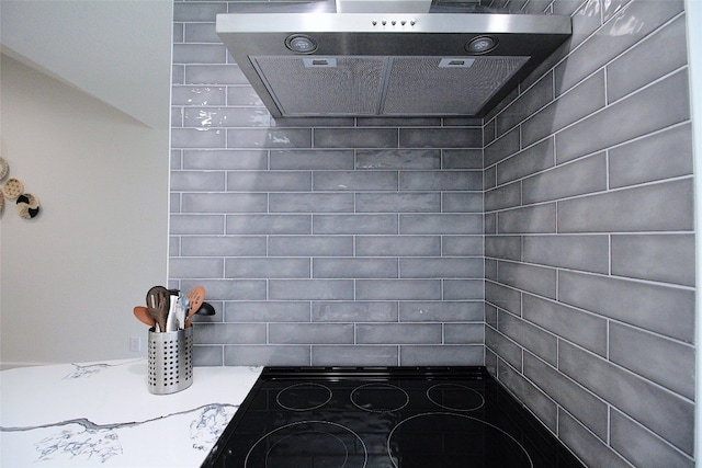 room details featuring wall chimney exhaust hood and black stovetop