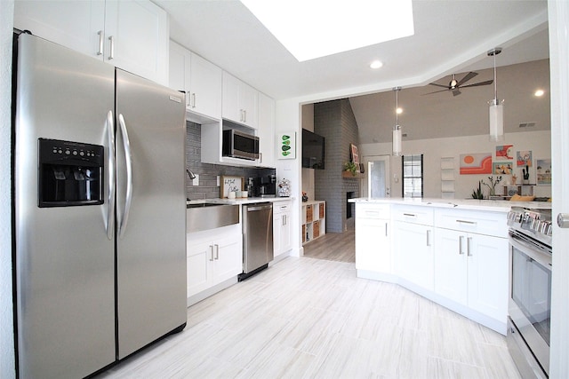 kitchen with a fireplace, ceiling fan, tasteful backsplash, appliances with stainless steel finishes, and white cabinetry