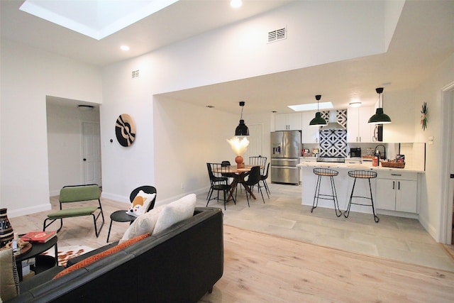 living room with a skylight, sink, and light hardwood / wood-style flooring