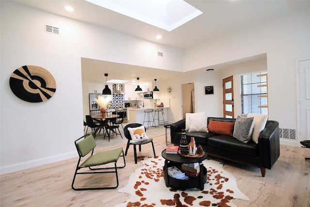 living room with light hardwood / wood-style floors, sink, and a skylight