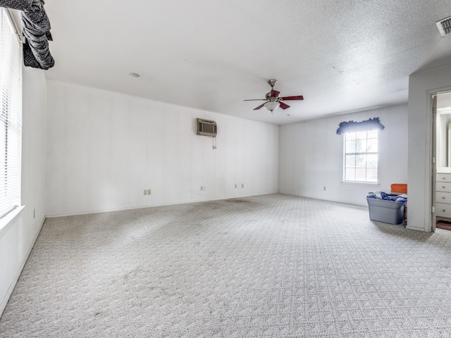 empty room with ceiling fan, a wall mounted AC, a textured ceiling, and carpet floors