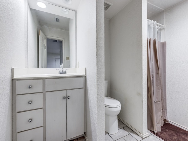 bathroom featuring tile patterned flooring, vanity, and toilet