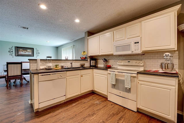 kitchen with kitchen peninsula, white appliances, light hardwood / wood-style floors, sink, and tasteful backsplash