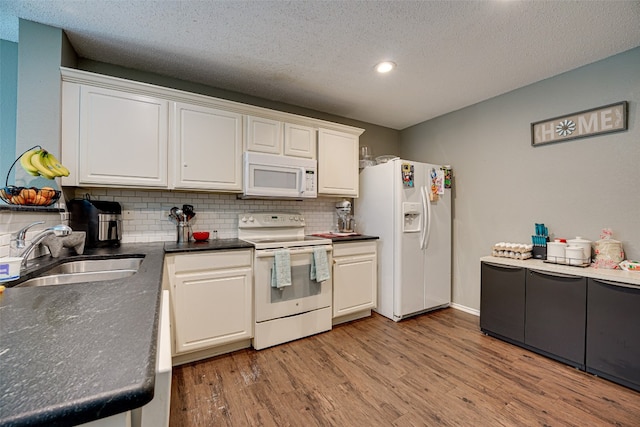 kitchen featuring tasteful backsplash, white cabinets, light wood-type flooring, white appliances, and sink