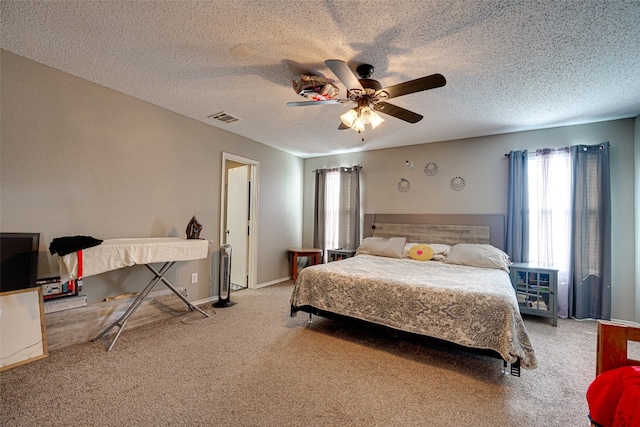 carpeted bedroom featuring ceiling fan and a textured ceiling