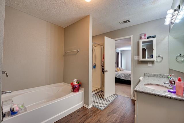 bathroom featuring a textured ceiling, plus walk in shower, wood-type flooring, and vanity