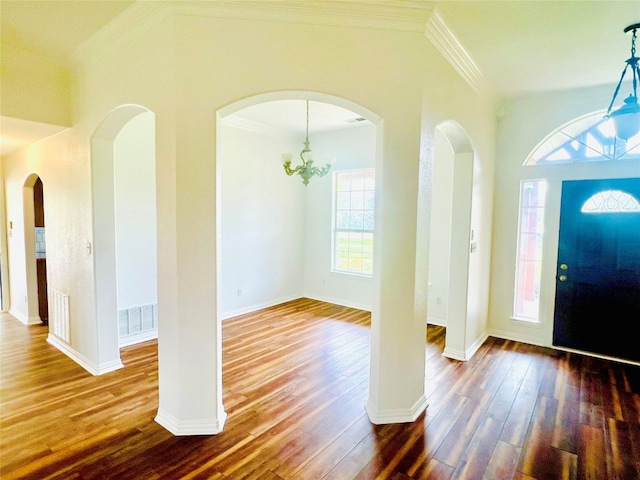 foyer entrance featuring crown molding, dark wood-type flooring, and an inviting chandelier