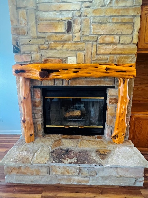 interior details featuring a stone fireplace and dark hardwood / wood-style flooring