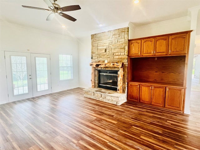 unfurnished living room featuring a stone fireplace, ceiling fan, dark hardwood / wood-style floors, and french doors