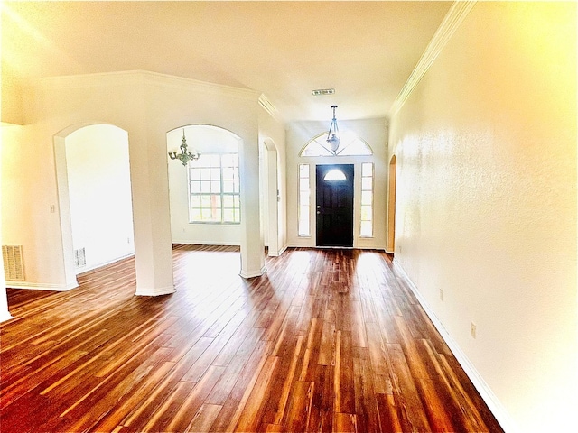 foyer with a chandelier, dark wood-type flooring, and ornamental molding