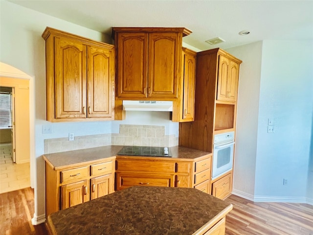 kitchen featuring white oven, black electric stovetop, and light tile floors