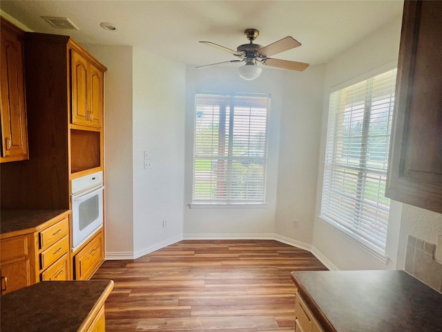 unfurnished dining area with plenty of natural light, dark wood-type flooring, and ceiling fan